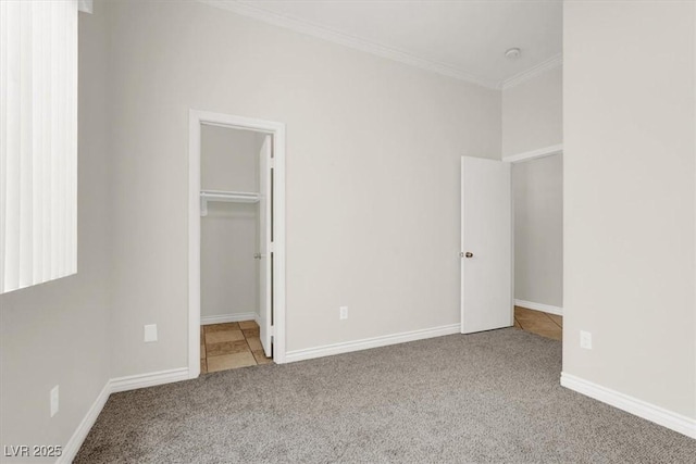 unfurnished bedroom featuring carpet flooring, crown molding, and a walk in closet