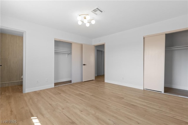 unfurnished bedroom featuring multiple closets and light hardwood / wood-style floors