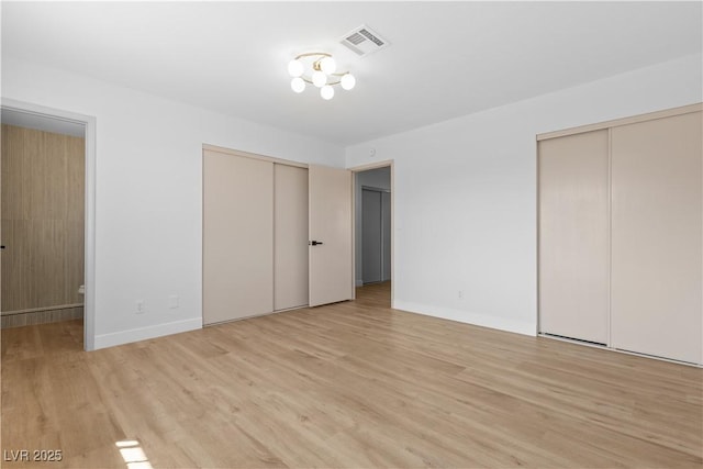 unfurnished bedroom featuring two closets and light hardwood / wood-style flooring