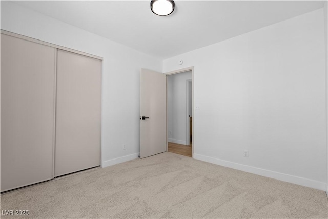 unfurnished bedroom with light colored carpet and a closet