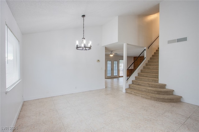 unfurnished room with french doors, a towering ceiling, and a textured ceiling