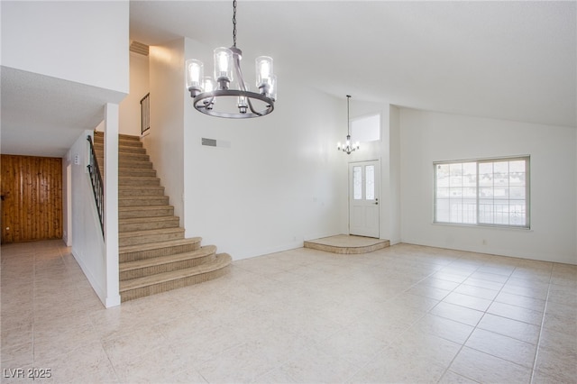 foyer entrance featuring an inviting chandelier, wooden walls, light tile patterned flooring, and a high ceiling