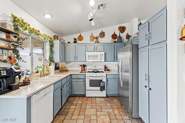 kitchen featuring blue cabinetry, lofted ceiling, sink, and white appliances