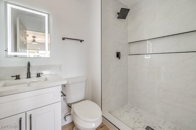 bathroom with vanity, toilet, and a tile shower