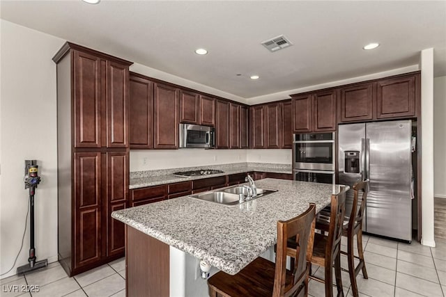 kitchen featuring sink, a breakfast bar area, a kitchen island with sink, light tile patterned floors, and stainless steel appliances