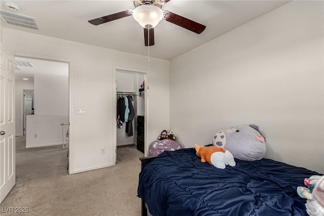 carpeted bedroom featuring ceiling fan, a walk in closet, and a closet