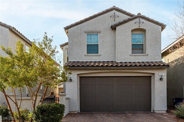 view of front of house with stucco siding, an attached garage, a tile roof, and decorative driveway