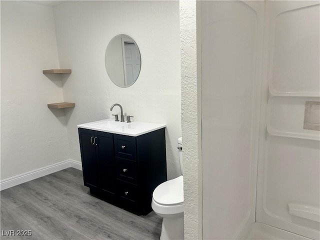 full bathroom featuring toilet, baseboards, wood finished floors, and vanity