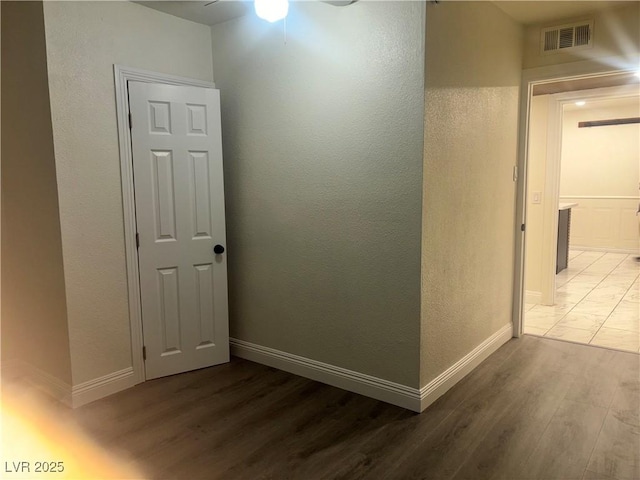 hallway featuring light wood-style floors, baseboards, and visible vents