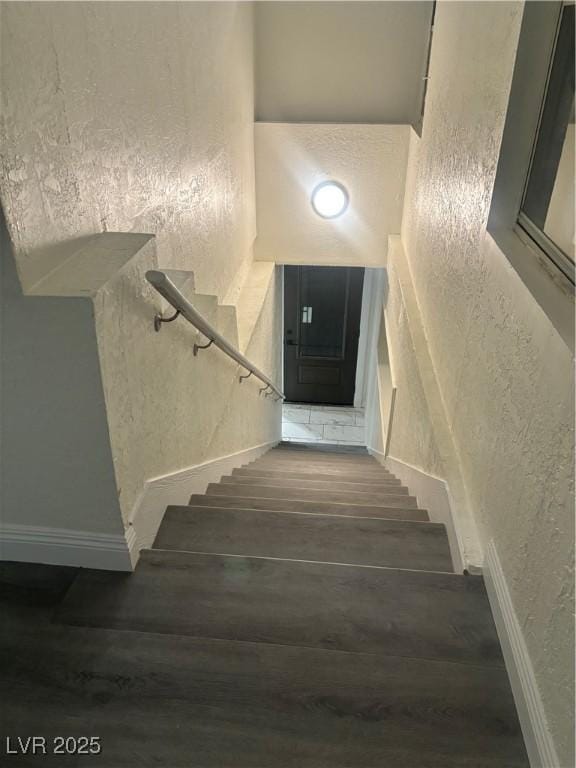 stairway featuring a textured wall and wood finished floors