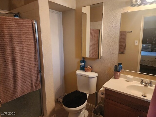 bathroom featuring vanity, toilet, and tiled shower