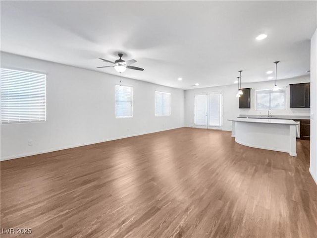 unfurnished living room with dark hardwood / wood-style flooring, sink, and ceiling fan