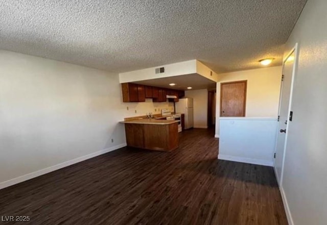 kitchen featuring a textured ceiling, electric range, white refrigerator, dark hardwood / wood-style flooring, and kitchen peninsula