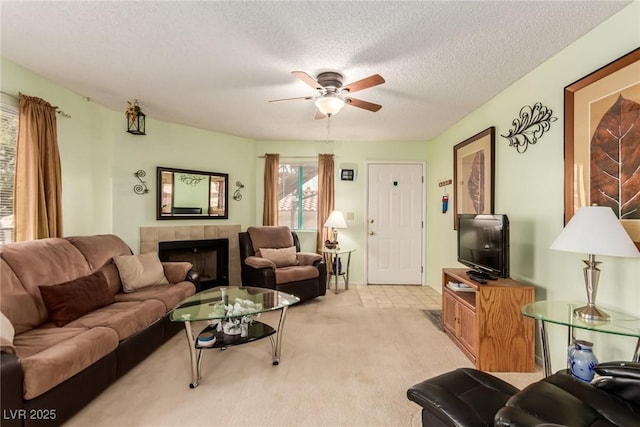 living room with light carpet, ceiling fan, a fireplace, and a textured ceiling