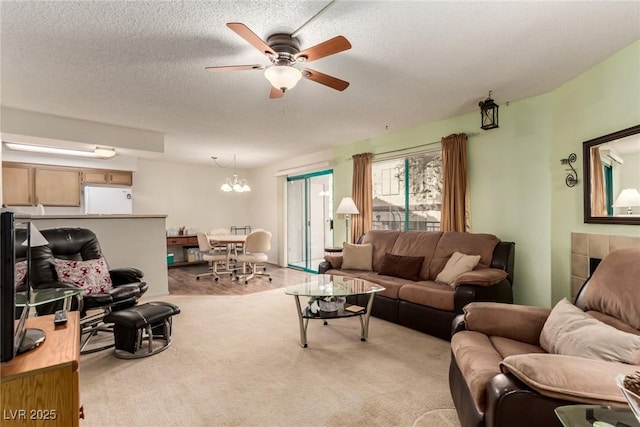 carpeted living room featuring ceiling fan with notable chandelier and a textured ceiling