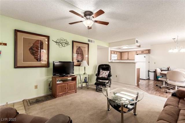 carpeted living room featuring ceiling fan with notable chandelier and a textured ceiling