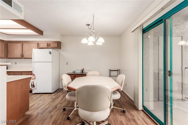 dining area featuring a notable chandelier, light hardwood / wood-style flooring, and a textured ceiling