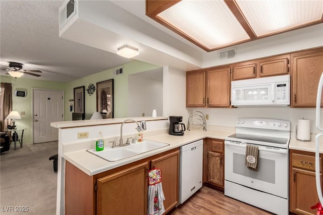 kitchen with sink, white appliances, ceiling fan, kitchen peninsula, and light wood-type flooring