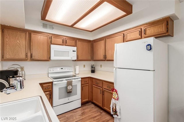 kitchen with white appliances, light hardwood / wood-style floors, and sink