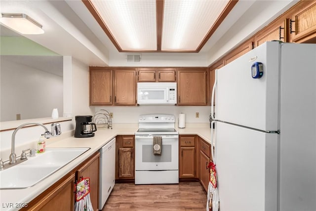 kitchen with sink, white appliances, and light hardwood / wood-style floors