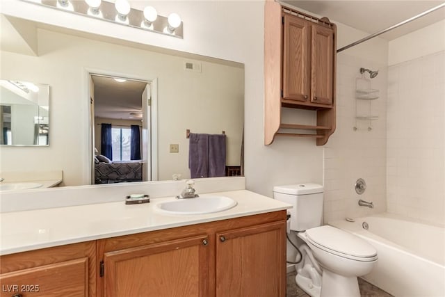 full bathroom featuring vanity, tiled shower / bath, and toilet