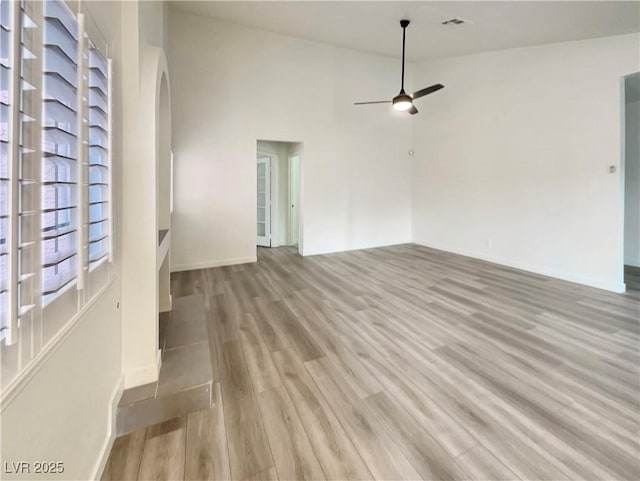 unfurnished living room featuring ceiling fan, high vaulted ceiling, and light wood-type flooring