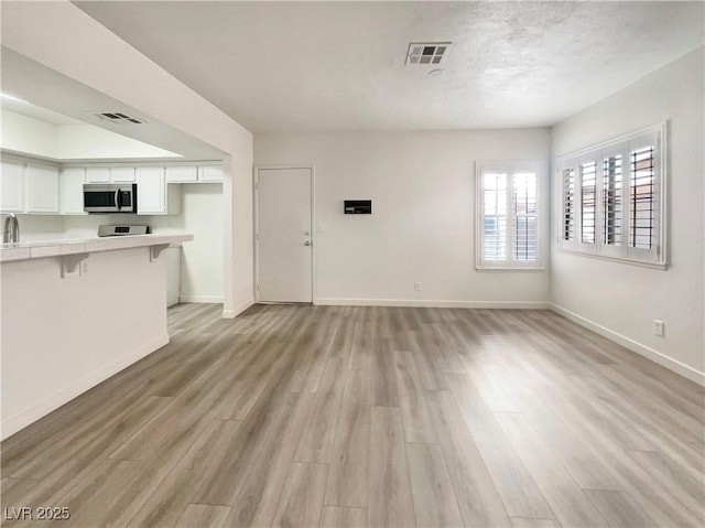 unfurnished living room with sink and light hardwood / wood-style flooring