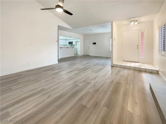 unfurnished living room featuring ceiling fan, light hardwood / wood-style floors, and vaulted ceiling