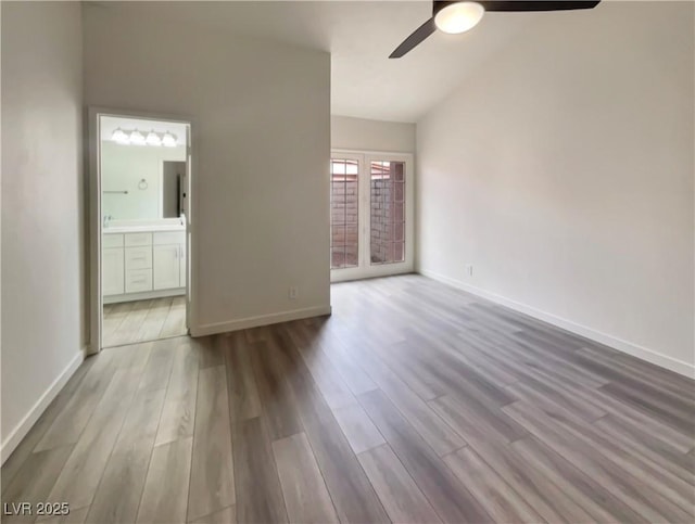 empty room with ceiling fan, lofted ceiling, and light wood-type flooring