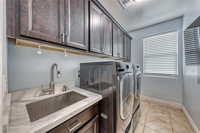 clothes washing area with sink, cabinets, light tile patterned floors, a textured ceiling, and washer and clothes dryer