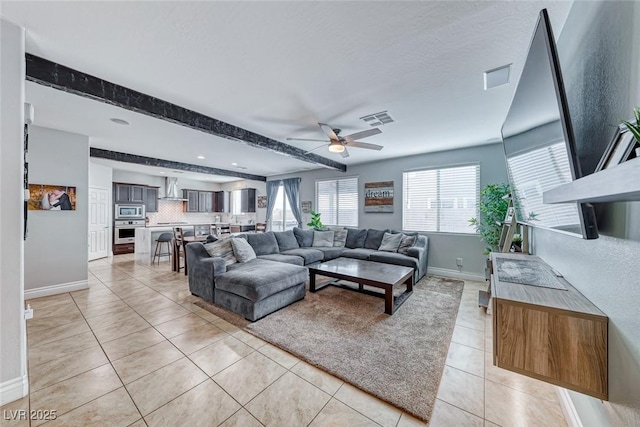 living room with beamed ceiling, light tile patterned floors, and ceiling fan