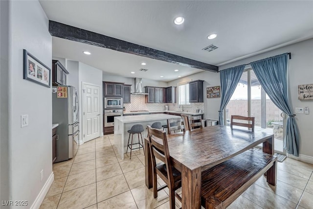 dining room featuring sink, beamed ceiling, and light tile patterned flooring