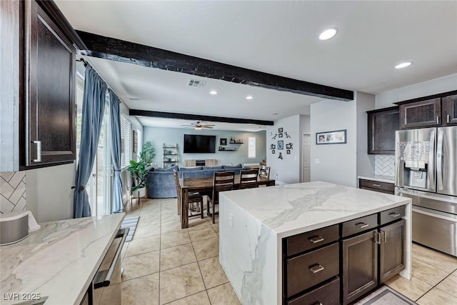 kitchen with tasteful backsplash, stainless steel fridge, light stone countertops, and beam ceiling