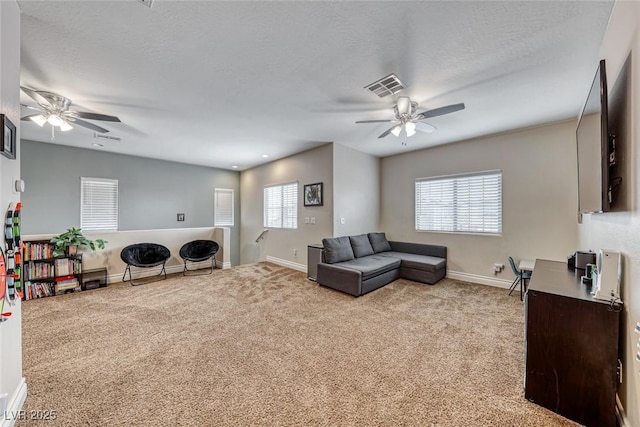 living room featuring ceiling fan, a healthy amount of sunlight, light carpet, and a textured ceiling