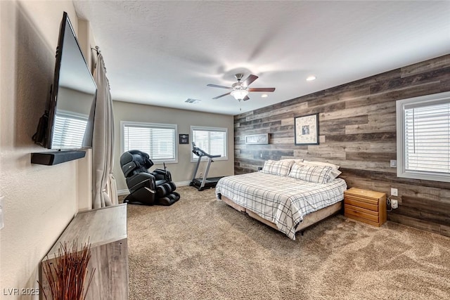 bedroom featuring carpet floors, wooden walls, and ceiling fan