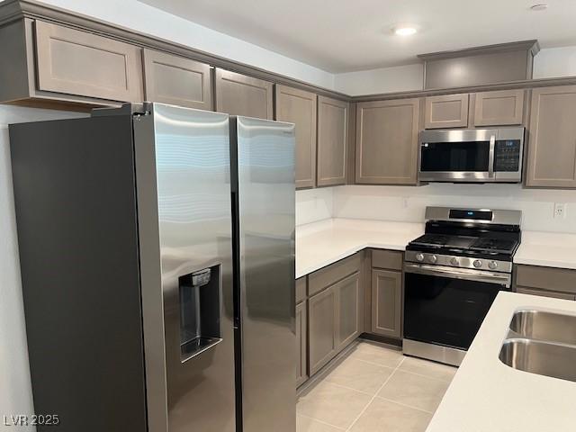 kitchen with stainless steel appliances, sink, and light tile patterned floors