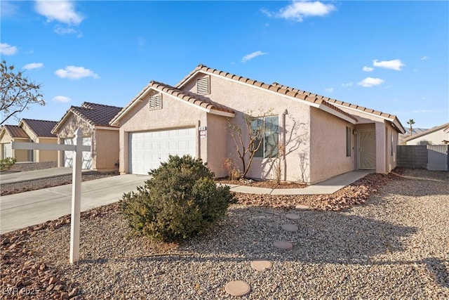 view of front of house featuring a tile roof, stucco siding, concrete driveway, fence, and a garage