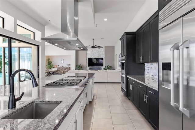 kitchen featuring sink, stainless steel appliances, light stone countertops, white cabinets, and island exhaust hood