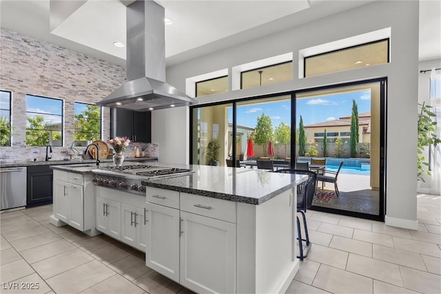 kitchen with backsplash, stainless steel appliances, island range hood, a kitchen island, and dark stone counters