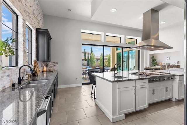 kitchen featuring sink, dark stone countertops, white cabinets, island exhaust hood, and stainless steel appliances