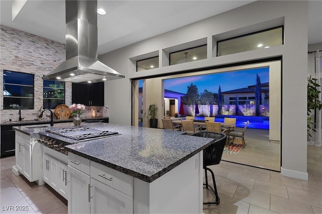 kitchen featuring white cabinetry, tasteful backsplash, island range hood, a center island, and stainless steel gas stovetop