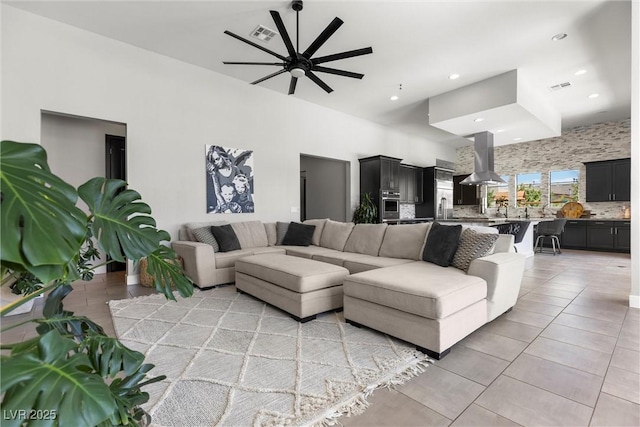 living room featuring ceiling fan, a towering ceiling, and light tile patterned floors