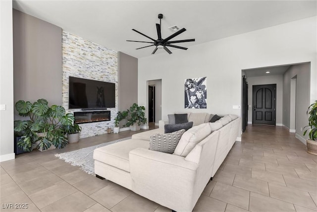 living room featuring a stone fireplace and ceiling fan