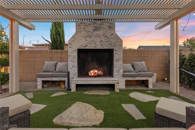 patio terrace at dusk with a pergola and an outdoor stone fireplace