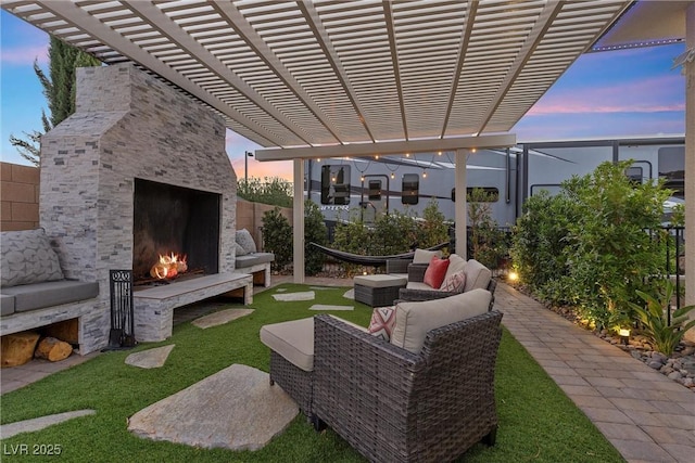 patio terrace at dusk with a pergola and an outdoor living space with a fireplace