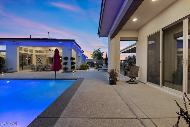 pool at dusk featuring a patio area