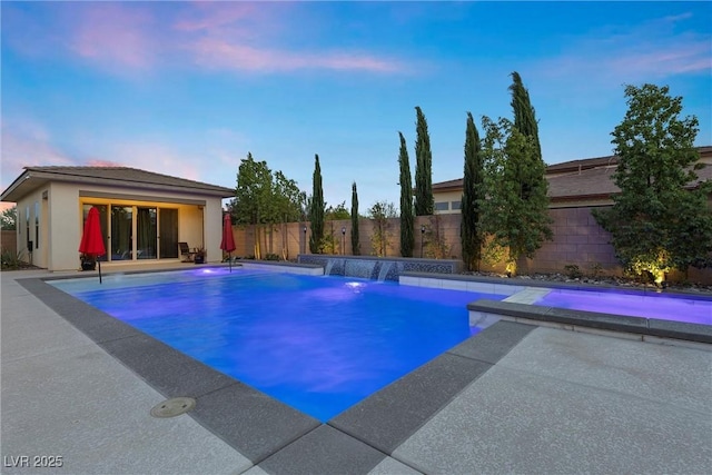 pool at dusk featuring a patio area and pool water feature