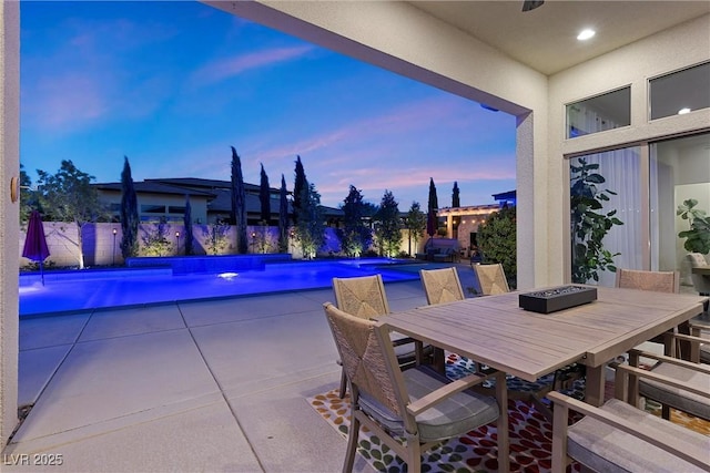 pool at dusk with pool water feature and a patio area