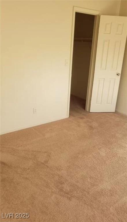 unfurnished bedroom with a spacious closet, a closet, and carpet flooring