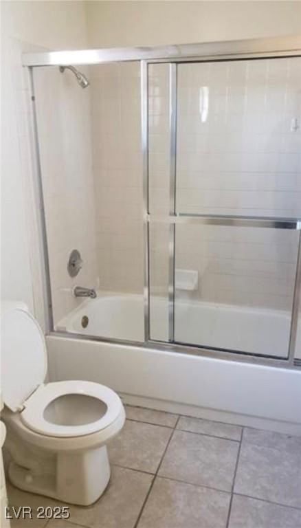 bathroom with tile patterned floors, shower / bath combination with glass door, and toilet